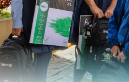 Estudiantes sostienen blocs de acuarela y mochilas, vistos de pecho para abajo