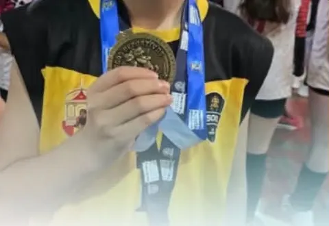 Estudiante con uniforme deportivo sostiene su medalla junto al pecho